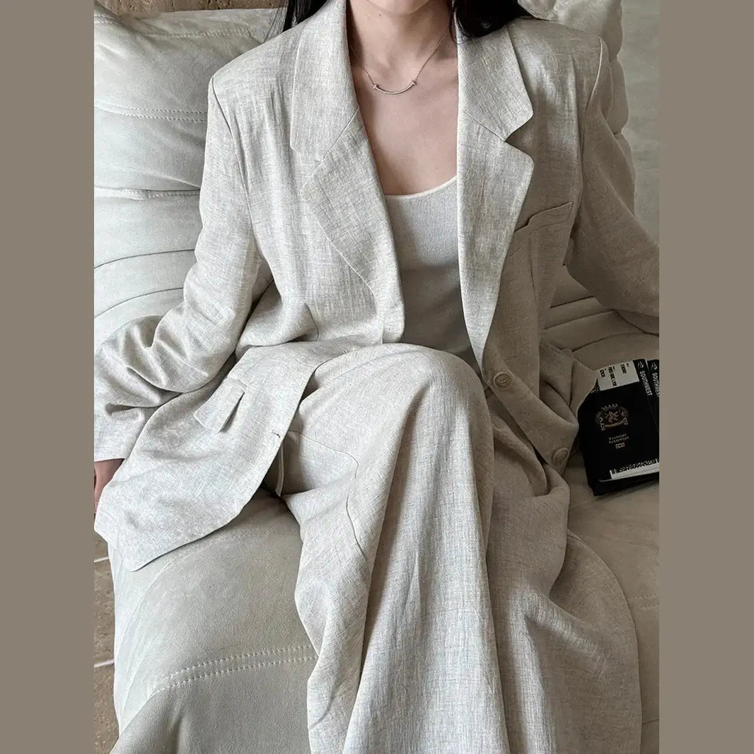 Person wearing a light gray suit sitting on a couch.