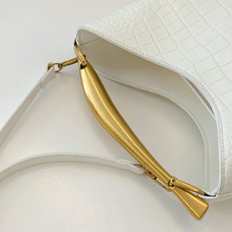 White handbag with gold handle on a light gray background