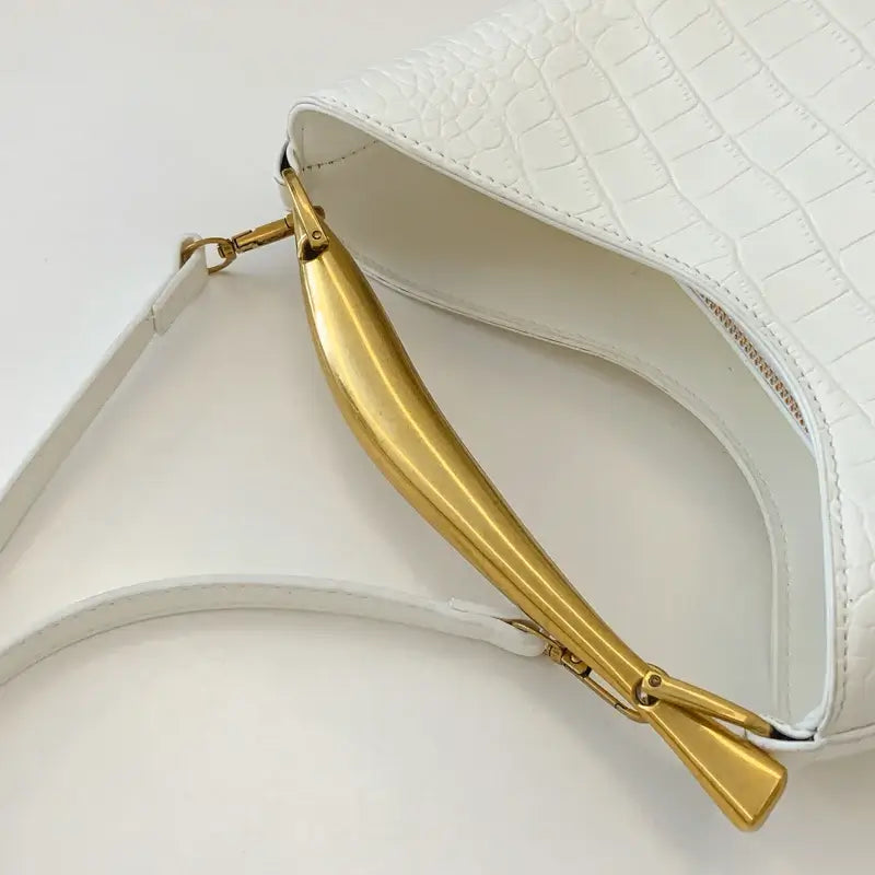 White handbag with gold handle on a light gray background