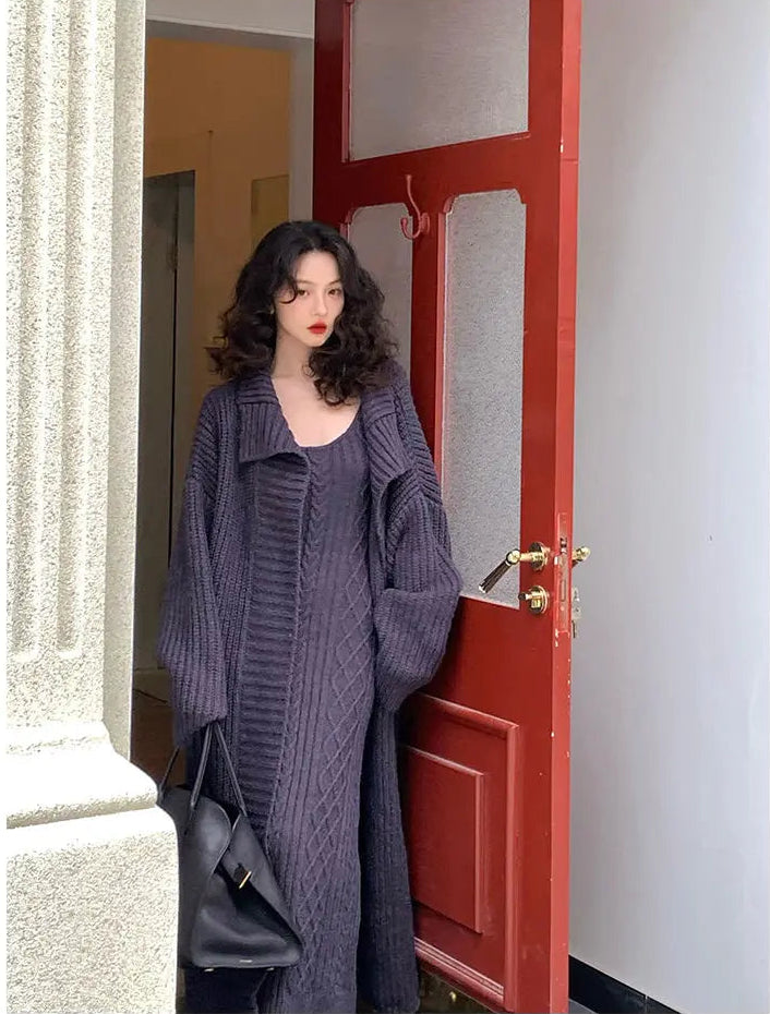Woman in a long gray coat standing in front of a red door.