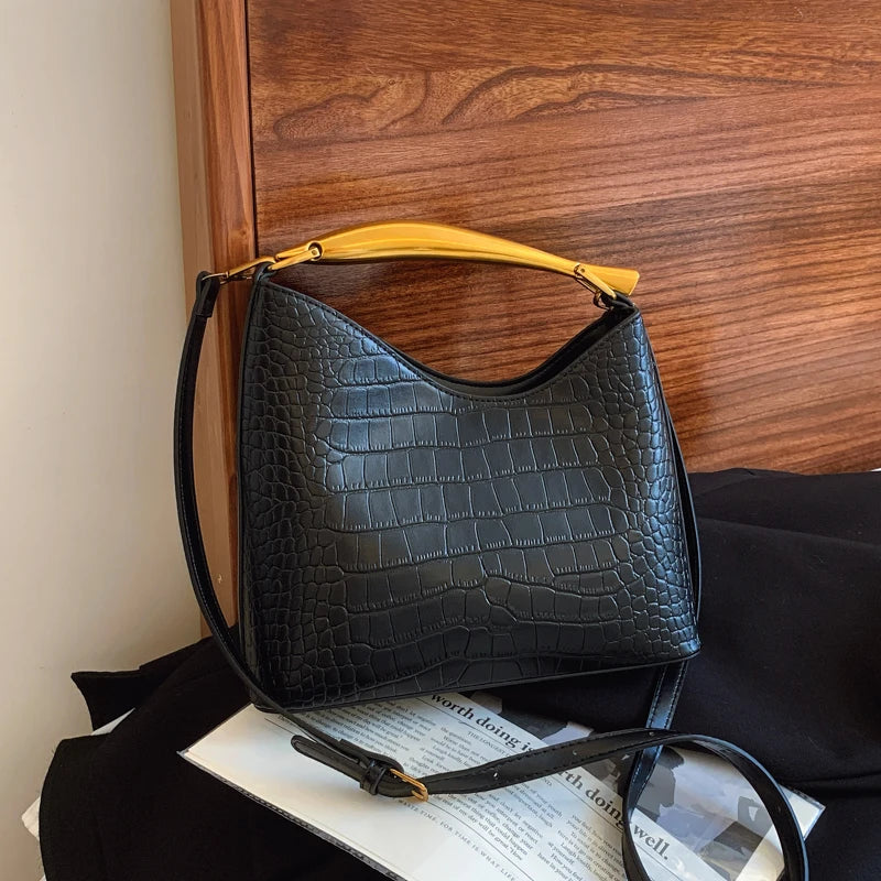Black textured handbag with yellow handle on a surface with a wooden background