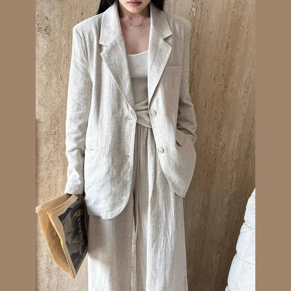 Person wearing a light-colored blazer and dress against a beige wall