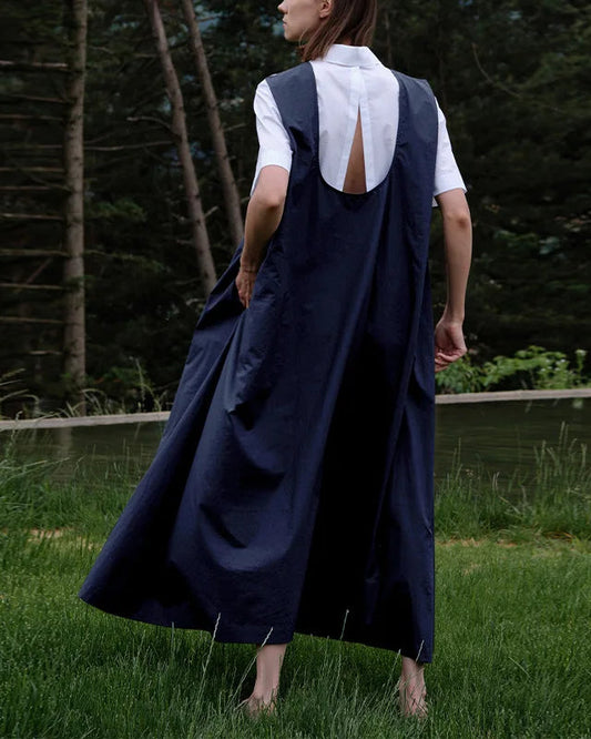 Front view of a woman wearing an elegant sleeveless linen A-line maxi dress in a natural setting.