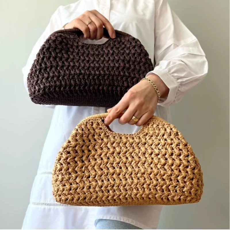 Person holding two woven handbags, one brown and one beige, against a plain background.