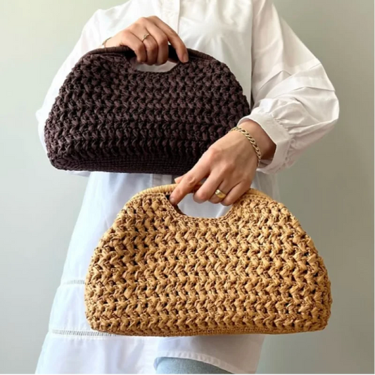 Person holding two woven handbags, one brown and one beige, against a plain background.