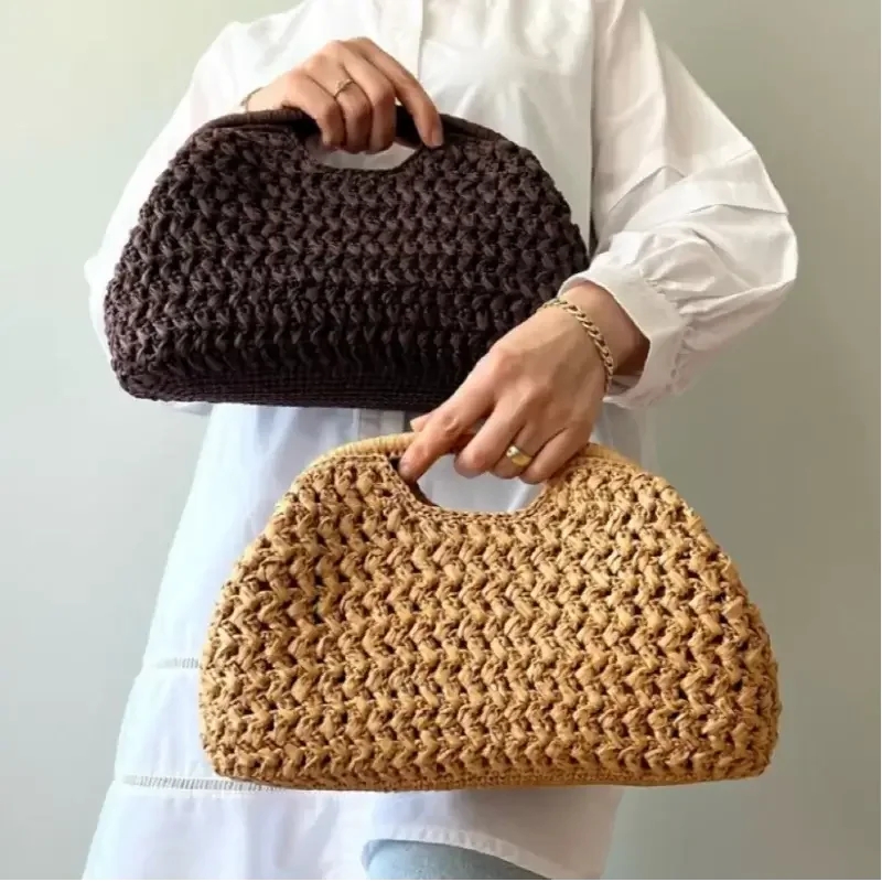 Person holding two woven handbags, one brown and one beige, against a plain background.