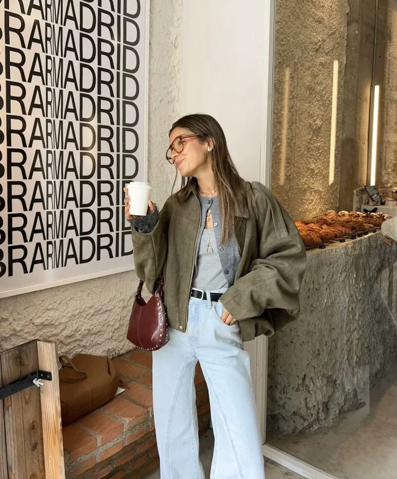Woman holding a coffee cup in front of a 'Bar Madrid' sign.