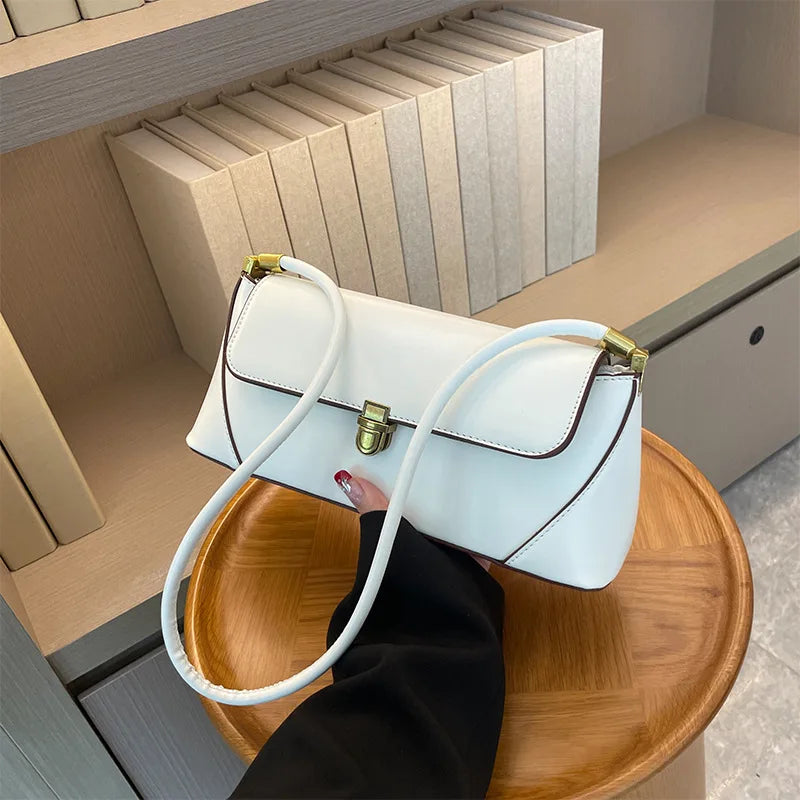 White handbag with a gold clasp on a wooden tray