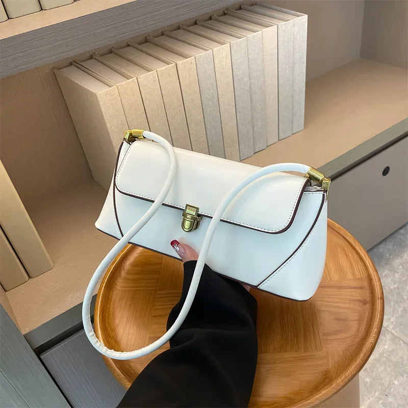White handbag with a gold clasp on a wooden tray