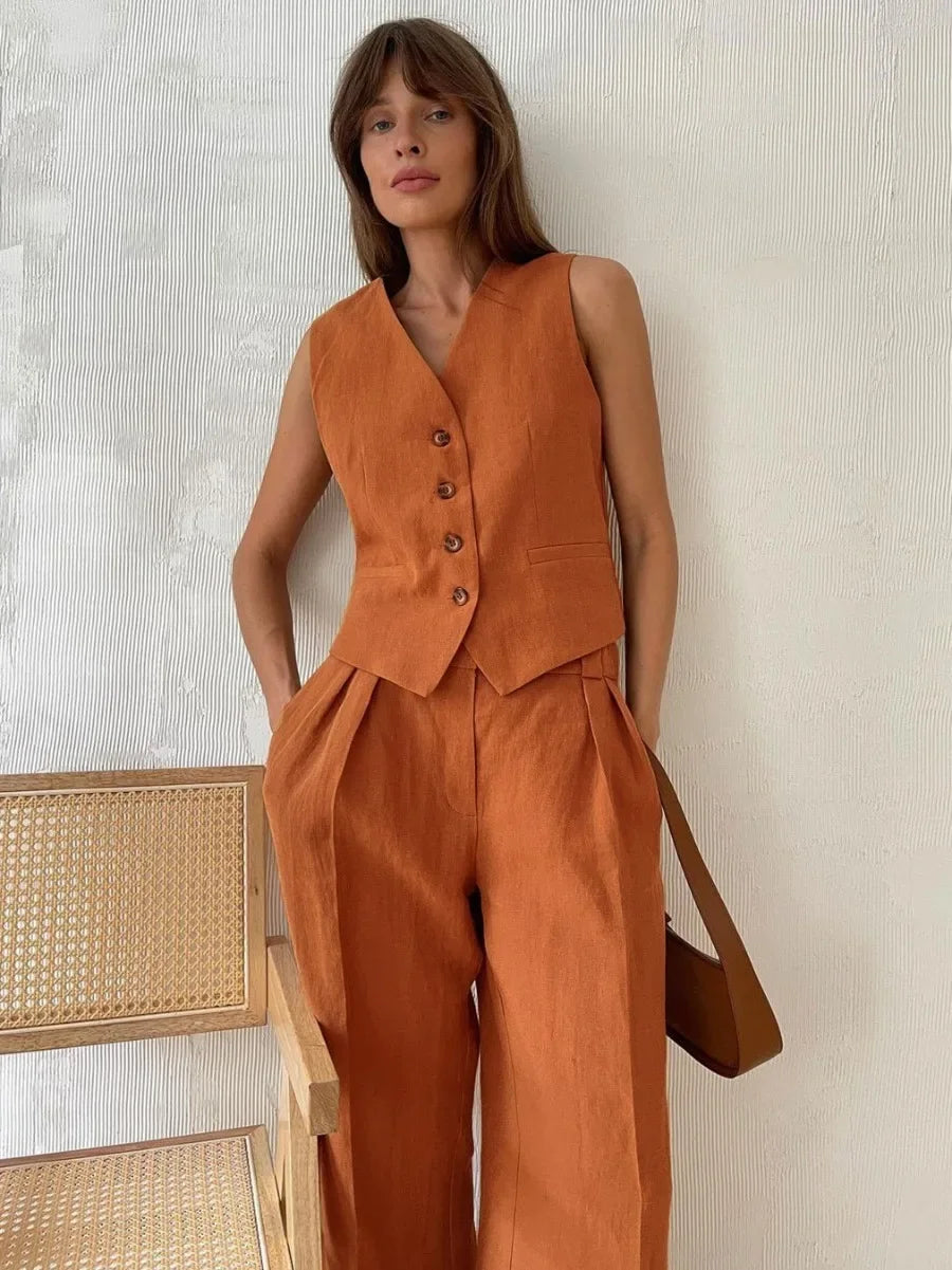 Woman wearing an orange vest and pants set with a neutral background
