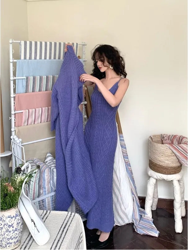 Woman in a blue dress holding a purple blanket next to a rack with various blankets.