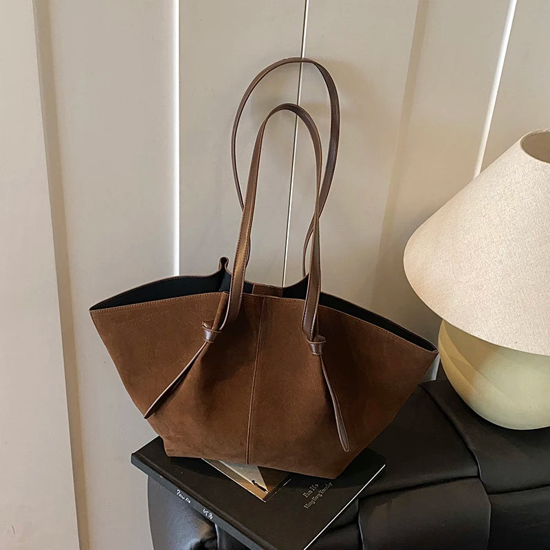 Brown handbag on a surface with a lamp in the background
