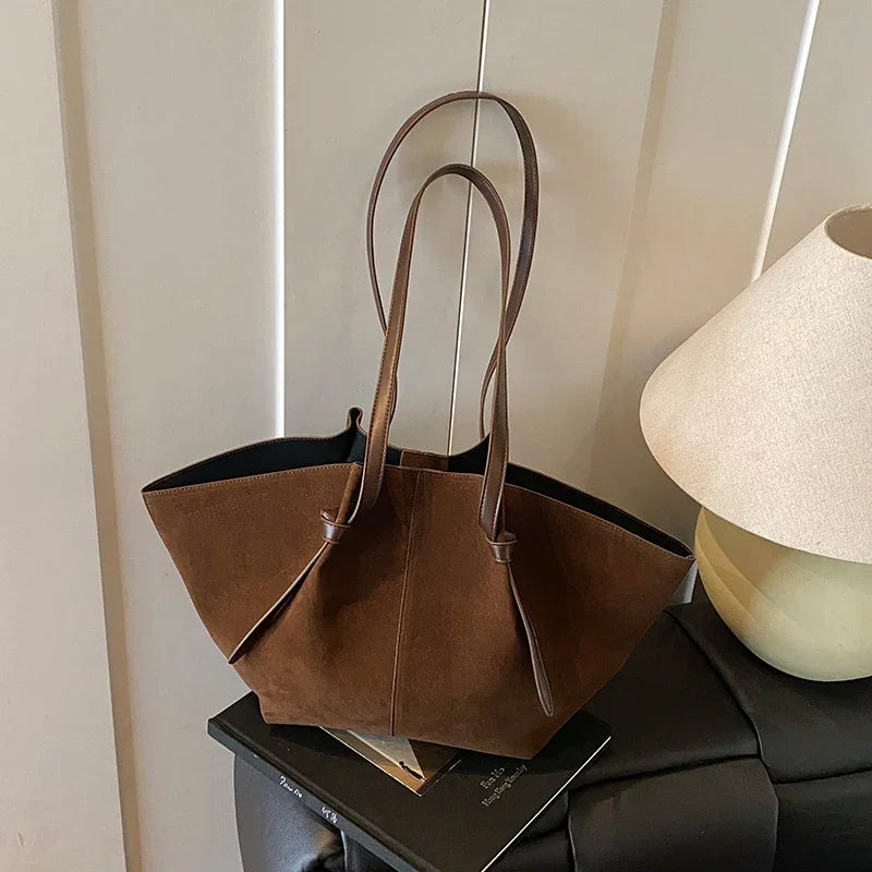 Brown handbag on a surface with a lamp in the background