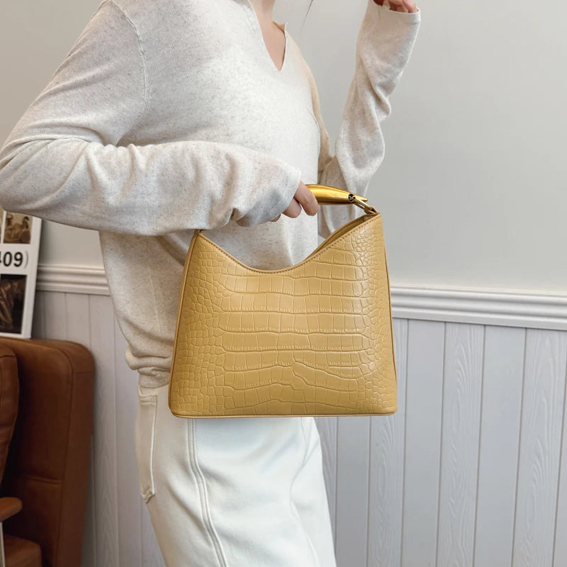 Person holding a yellow handbag against a neutral background
