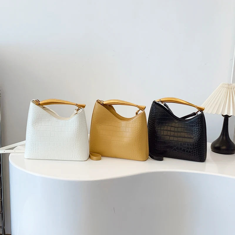 Three handbags in white, yellow, and black on a white surface with a neutral background