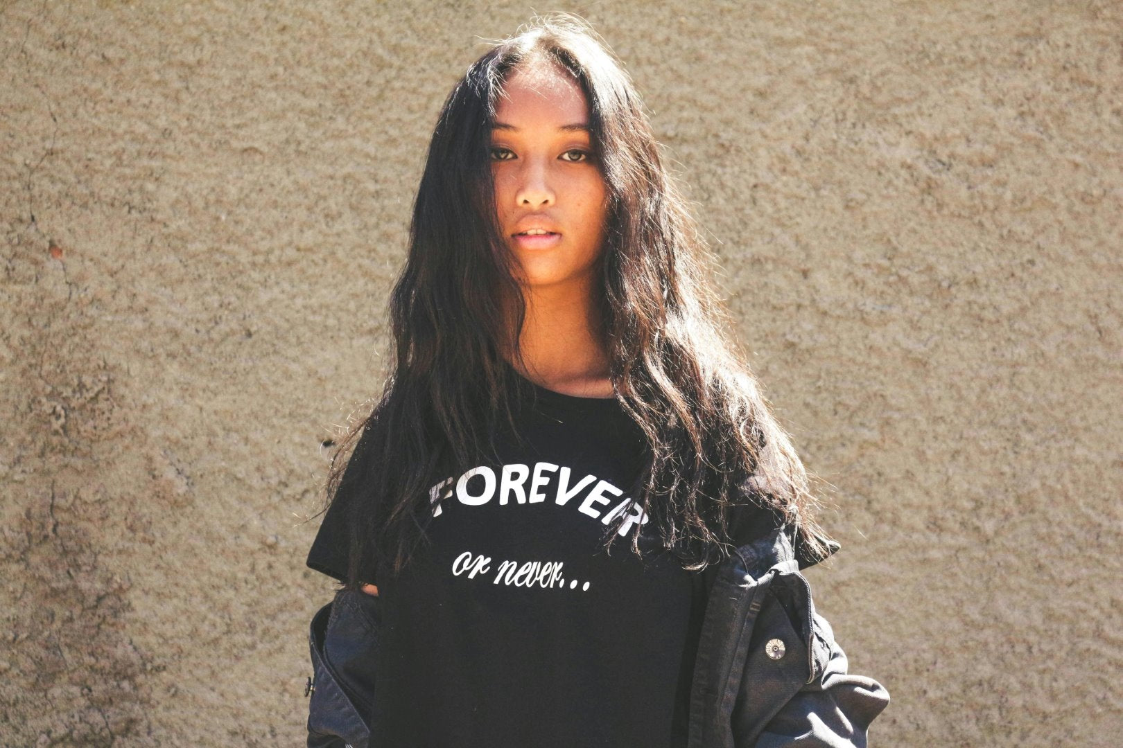 Person wearing a black t-shirt with text against a beige wall