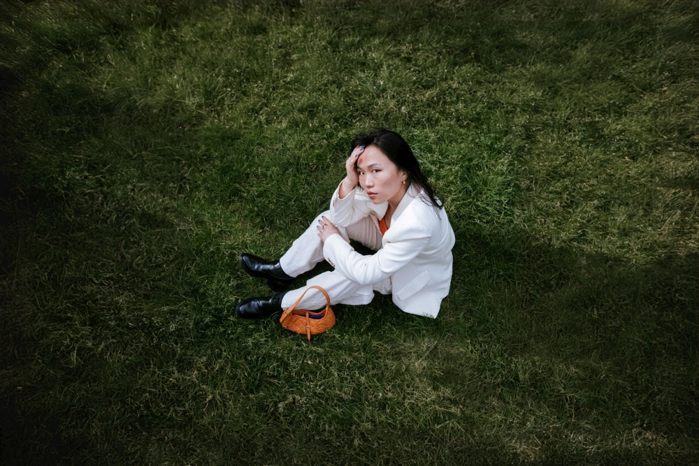 A woman in a white shirt is sitting on the grass.