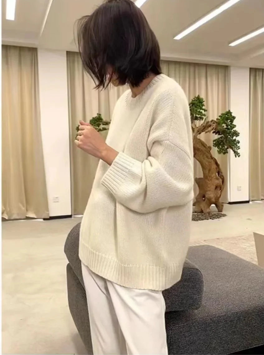 Front view of woman wearing the loose-fit pure cashmere crewneck sweater in undyed cream.