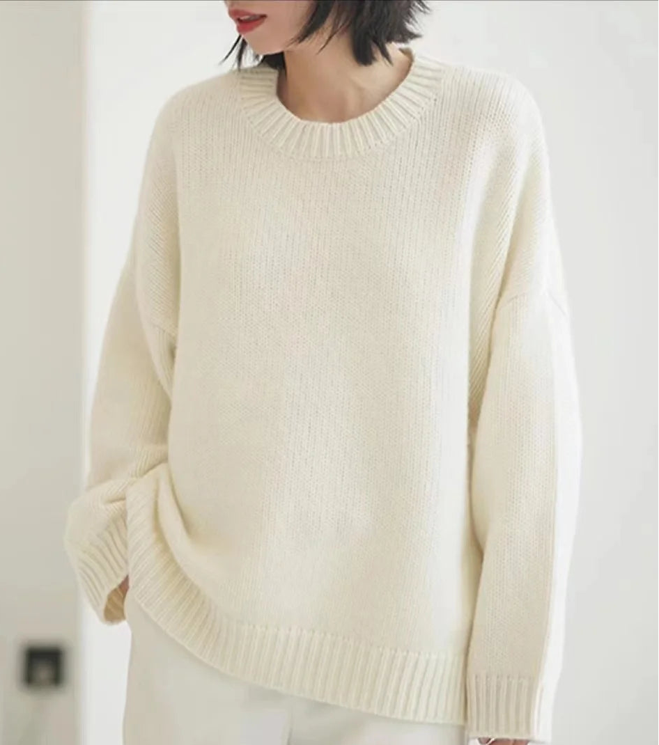Front view of woman wearing the loose-fit pure cashmere crewneck sweater in undyed cream.
