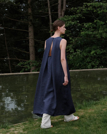 Front view of a woman wearing an elegant sleeveless linen A-line maxi dress in a natural setting.