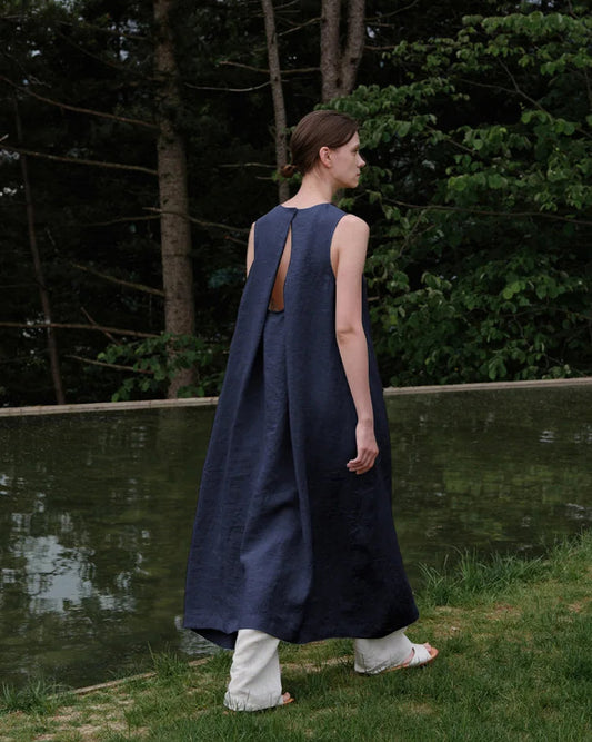 Front view of a woman wearing an elegant sleeveless linen A-line maxi dress in a natural setting.