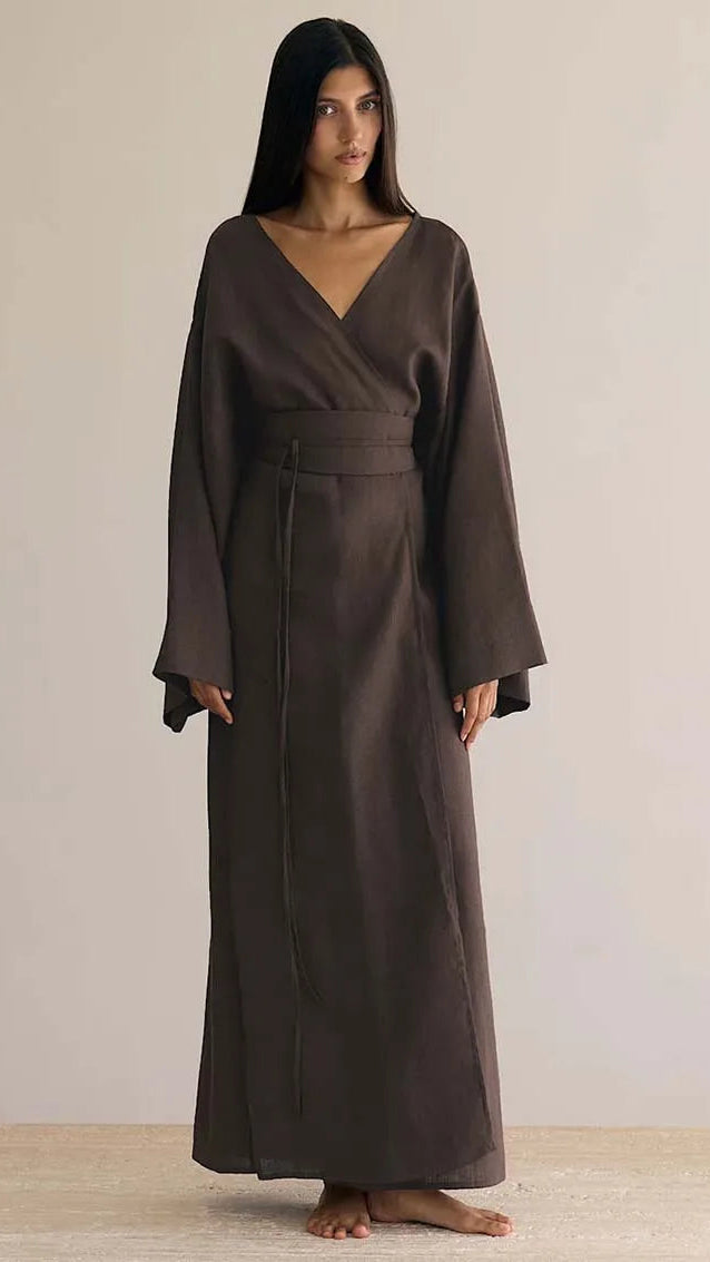 Woman wearing a long brown dress against a plain background