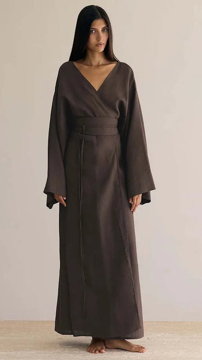 Woman wearing a long brown dress against a plain background