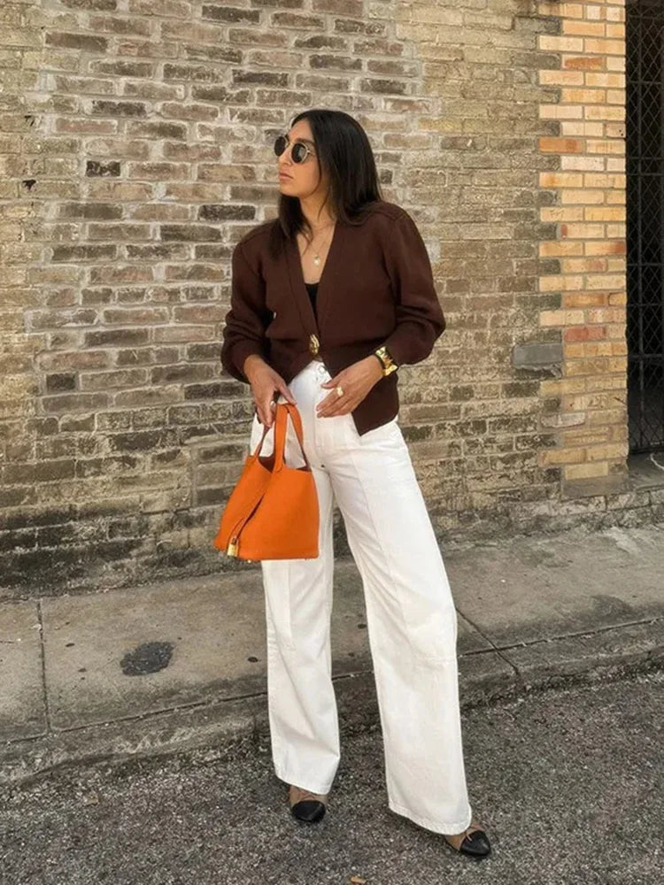 Woman holding an orange handbag against a brick wall