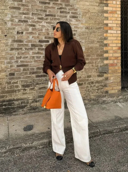 Woman holding an orange handbag against a brick wall