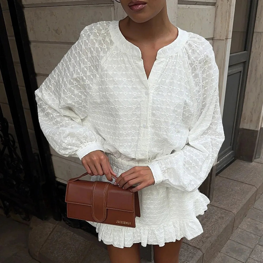 Person wearing a white dress holding a brown handbag on a sidewalk.