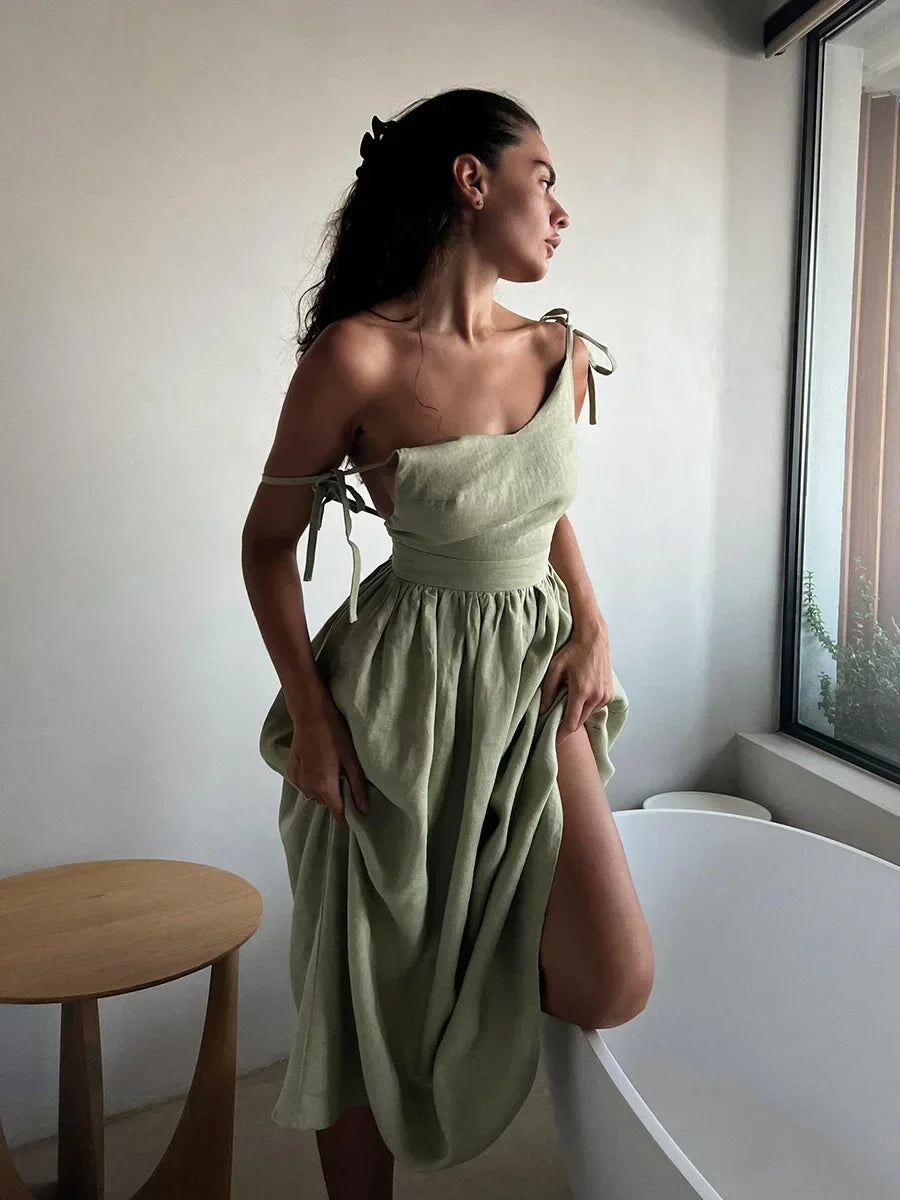Woman wearing a light green dress standing in a room with a window and table.