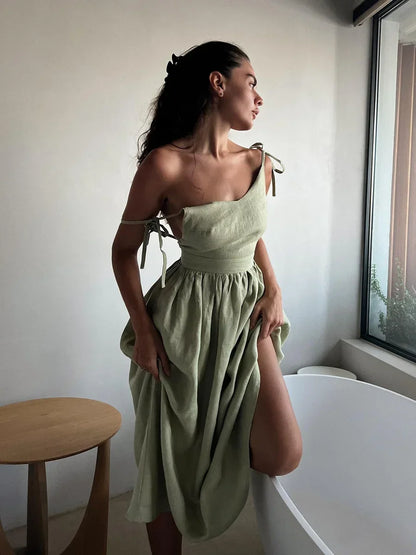 Woman wearing a light green dress standing in a room with a window and table.