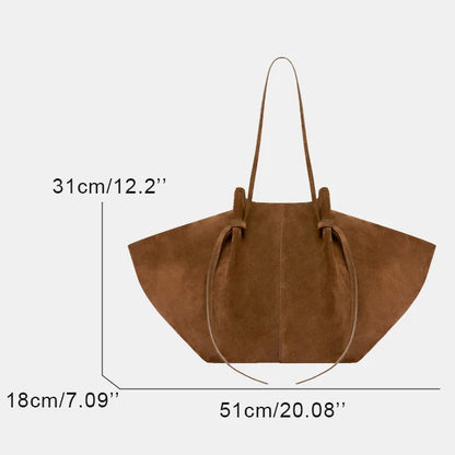A brown suede tote bag shown with dimension lines and text indicating measurements: 31 cm height, 18 cm width, and 51 cm base, on a light gray background.