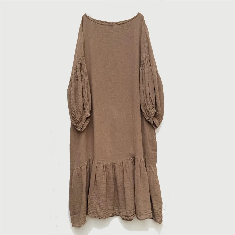 Front view of woman wearing loose-fit cotton linen midi dress in neutral tone with lantern sleeves