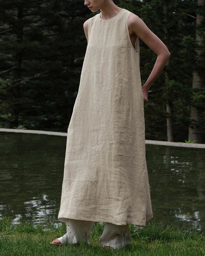 Front view of a woman wearing an elegant sleeveless linen A-line maxi dress in a natural setting.