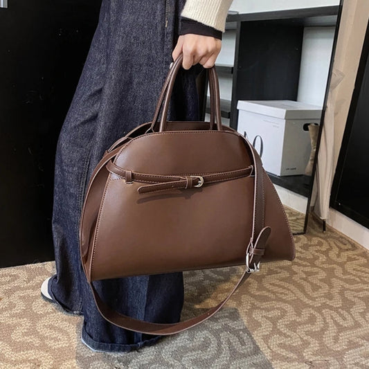 Person holding a brown handbag in an indoor setting with 'Moods Boutique' branding.