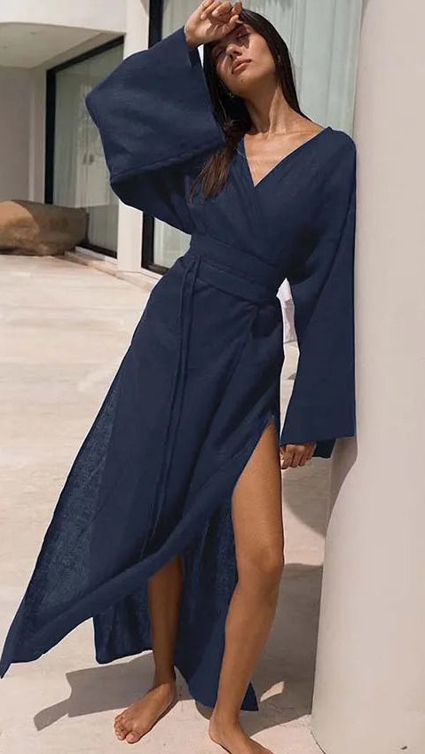 Woman wearing a navy blue dress with wide sleeves in an outdoor setting.