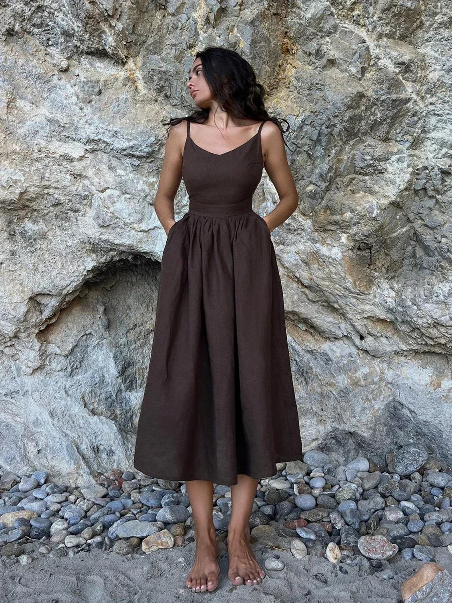 Woman in a brown dress standing against a rocky background