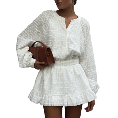 Woman wearing a white patterned dress holding a brown handbag on a white background