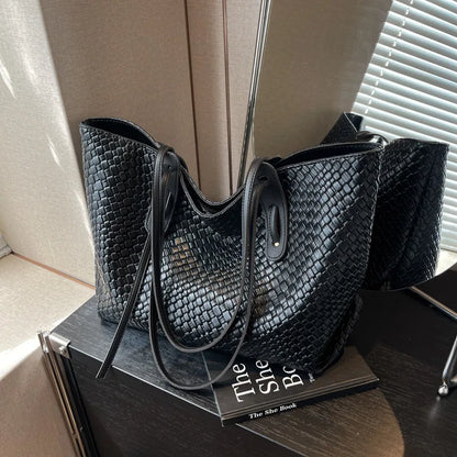 Black woven handbag on a book with a neutral background