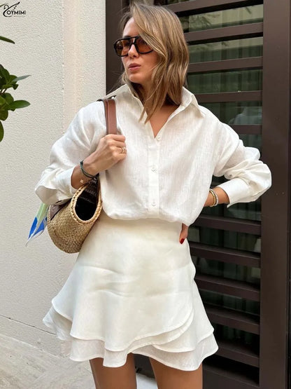 Woman in a white outfit holding a straw bag against a neutral background
