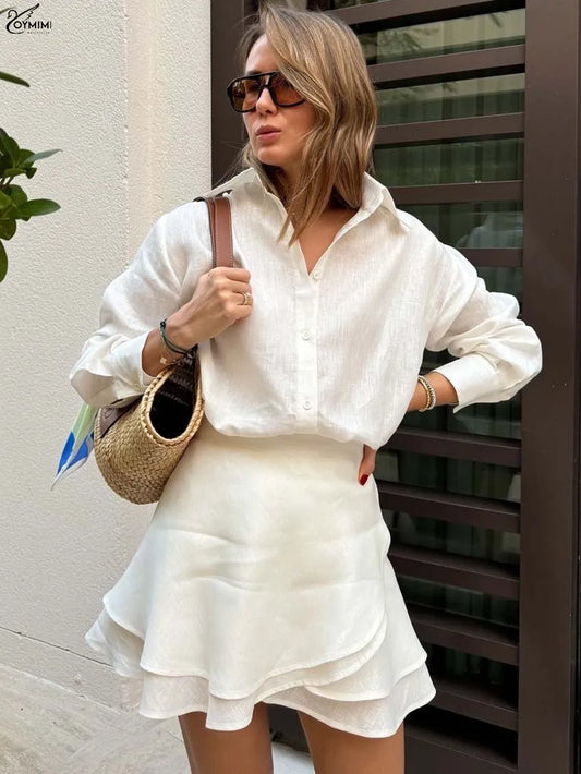 Woman in a white outfit holding a straw bag against a neutral background