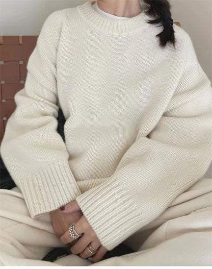 Front view of woman wearing the loose-fit pure cashmere crewneck sweater in undyed cream.