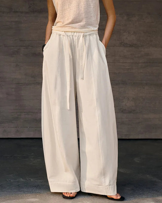 Person wearing light-colored wide-leg pants against a dark background