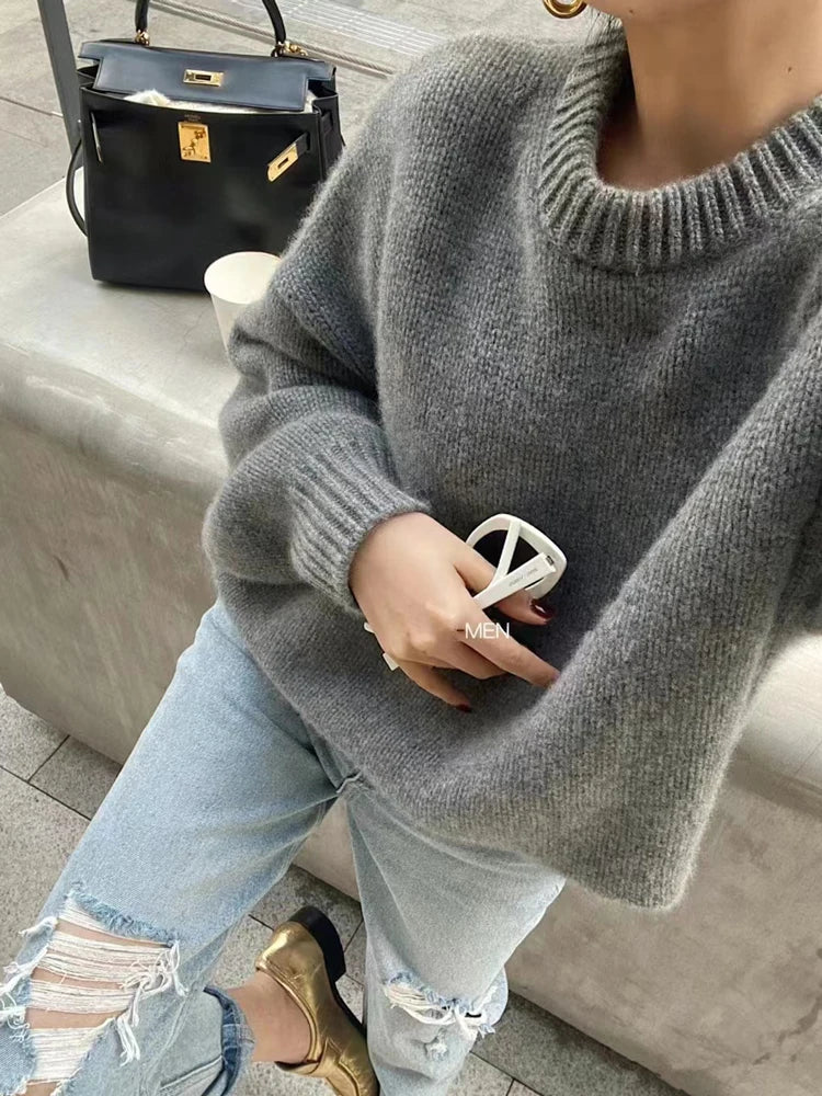 Front view of woman wearing the loose-fit pure cashmere crewneck sweater in undyed cream.