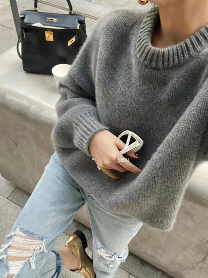 Front view of woman wearing the loose-fit pure cashmere crewneck sweater in undyed cream.